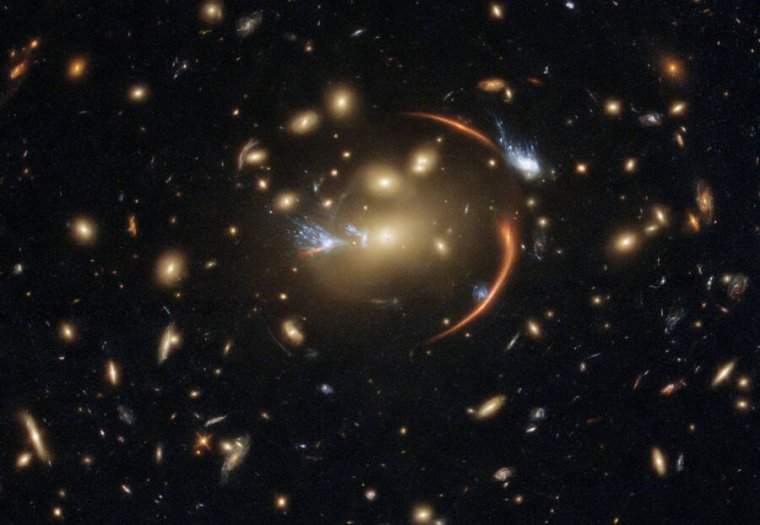 Image of many galaxies, with some distorted streaks near the center.